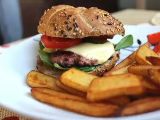 Pyszne, prawdziwe burgery przepis na domowy obiad. Soczysty kotlet, ser, warzywa i chrupiące frytki na talerzu.