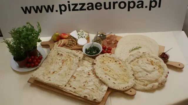 Gotowe ciasto na pizzę, świeże zioła, pomidorki, ser i inne dodatki na drewnianych deskach. Idealne na domowe wypieki.