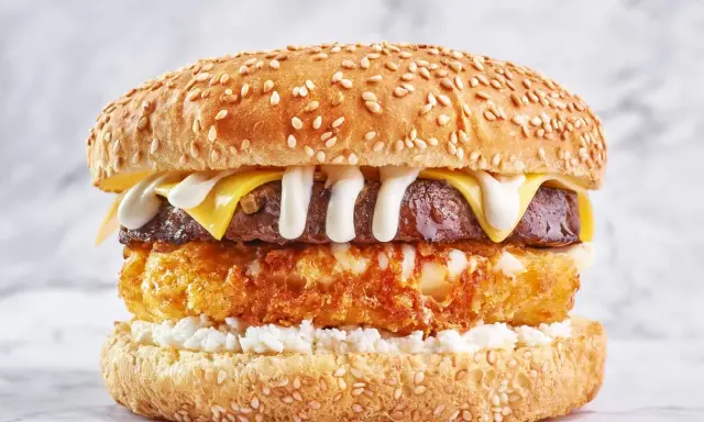 Apetyczny burger drwala przepis: soczysta wołowina, chrupiące panierowane ziemniaki, ser i biały sos na sezamowej bułce.