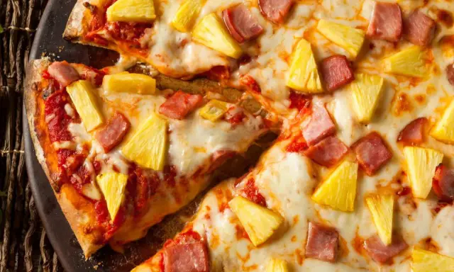 Pyszna pizza z ananasem i szynką, z ciągnącym się serem i chrupiącym ciastem. Idealna na szybki obiad.