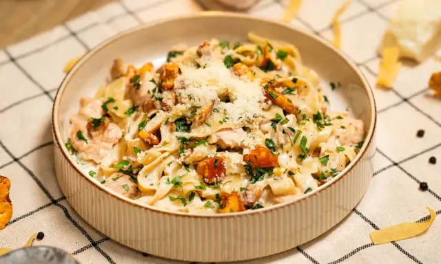 Pyszny makaron w sosie kurkowym z kawałkami kurczaka i posypany parmezanem.