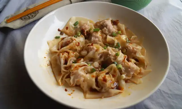 Pyszne pierożki wonton w pikantnym sosie, posypane szczypiorkiem i sezamem. Ciasto do wontonów jest cienkie i delikatne.