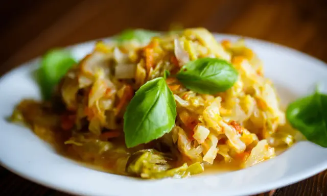 Pyszny bigos z młodej kapusty, duszony z marchewką i przyprawami, udekorowany listkami bazylii. Idealny przepis, jak ugotować dobry bigos z młodej kapusty.