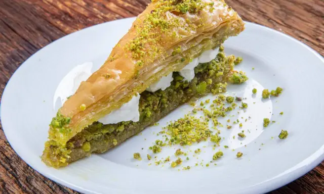 Pyszna baklawa z pistacjami i kremem na białym talerzu. Idealny przepis na deser.