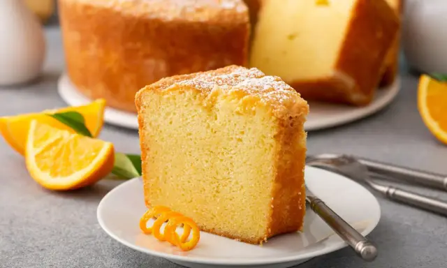 Puszysta babka cytrynowa, oprószona cukrem pudrem, z plasterkami pomarańczy. Idealna na niedzielne popołudnie, gdy szukasz przepisu na babkę wiszącą.
