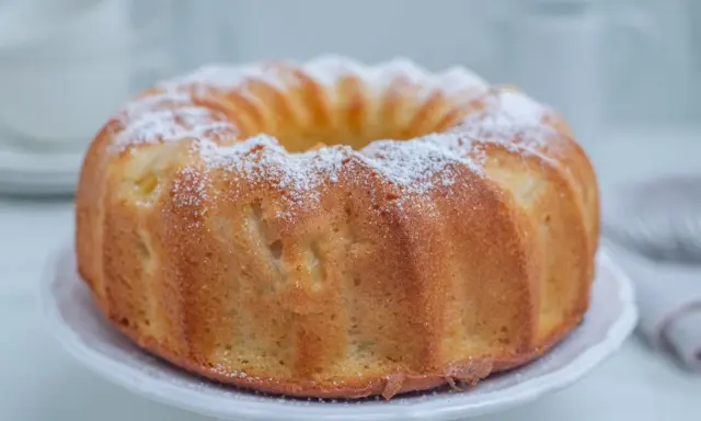 Szybka babka wilgotna, oprószona cukrem pudrem, prezentuje się apetycznie na białej paterze. Idealna na szybką przekąskę.