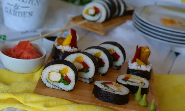 Pyszne sushi z kurczakiem, papryką i mango. Podane na desce z dodatkami: marynowanym imbirem i wasabi.