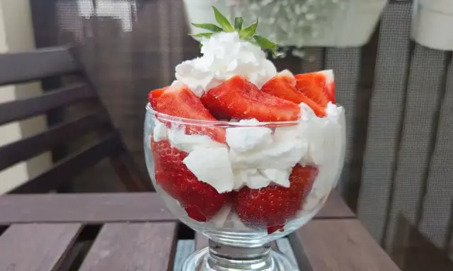 Pyszne, świeże truskawki ze śmietaną w pucharku, gotowe do schrupania.