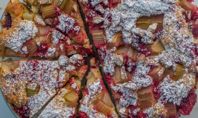 Pyszne ciasto z rabarbarem i malinami, posypane cukrem pudrem. Idealny przepis na letnie popołudnie.