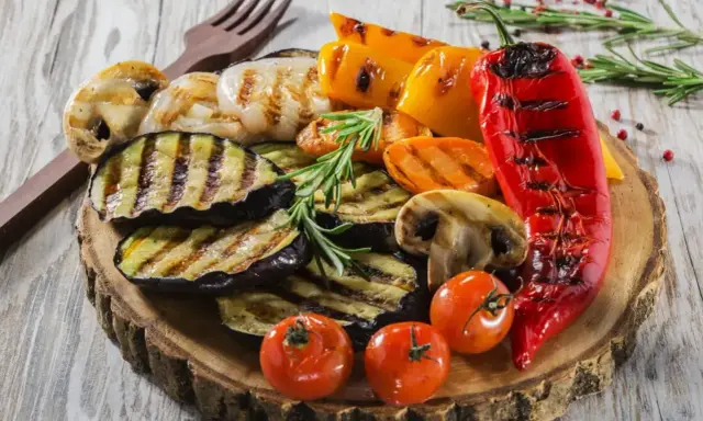Pyszne warzywa na grilla: grillowany bakłażan, papryka, pieczarki, pomidorki i czerwona papryka, udekorowane rozmarynem.