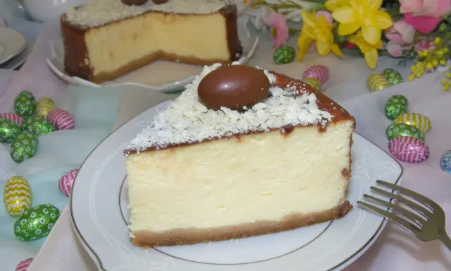 Wspaniały sernik z mascarpone, udekorowany czekoladowymi jajeczkami i wiórkami białej czekolady, idealny na Wielkanoc.