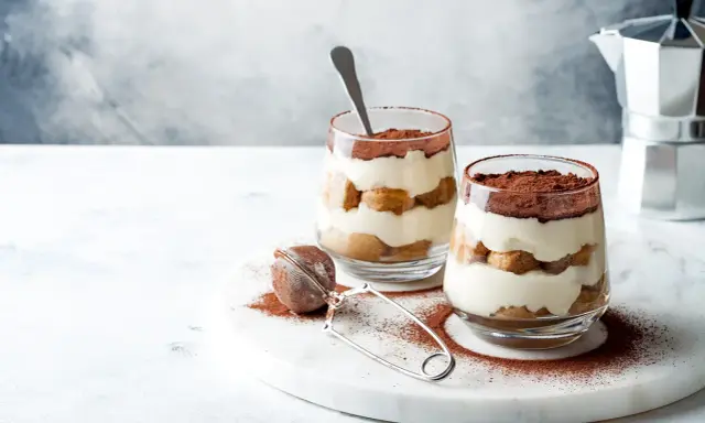 Dwa pucharki z kremowym, warstwowym deserem z biszkoptów i kakao. Idealne na najprostsze tiramisu.