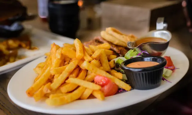 Porcja frytek z sosem i sałatką. Zastanawiasz się, ile kalorii ma porcja frytek?