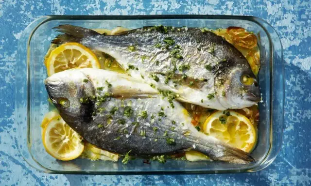Dwie dorady pieczone z cytryną i ziołami w szklanym naczyniu. To pyszna ryba, idealna na obiad.