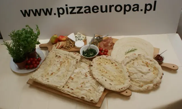 Gotowe ciasto na pizzę, świeże zioła, pomidorki, ser i inne dodatki na drewnianych deskach. Idealne na domowe wypieki.