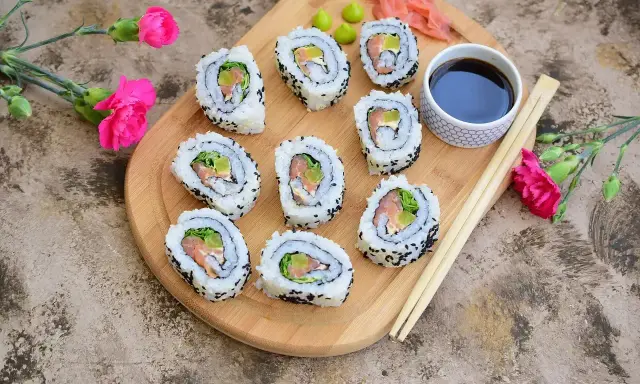 California sushi z łososiem i awokado, posypane czarnym sezamem, podane z sosem sojowym i wasabi.