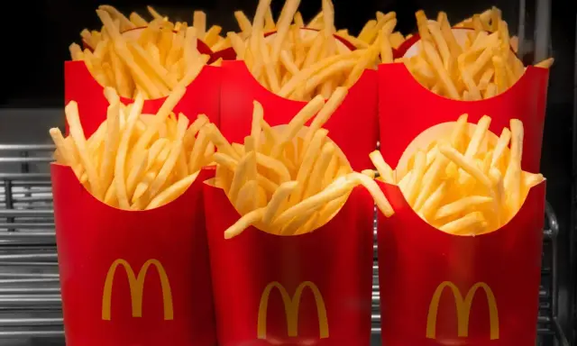 Rzędy czerwonych opakowań z logo McDonald's, wypełnione chrupiącymi frytkami. Zastanawiasz się, ile kosztują małe frytki w McDonald's?
