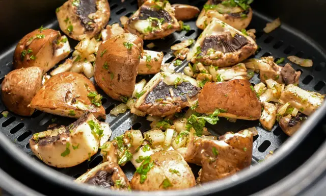Pyszne pieczarki z airfryer, przyprawione i posypane natką pietruszki, gotowe do podania.