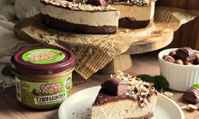 Pyszne ciasto kinder bueno z mascarpone, udekorowane orzechami i kawałkami czekolady. Obok słoik pasty z orzechów laskowych.