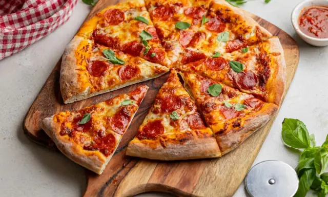 Pyszna pizza pepperoni z ciągnącym się serem i świeżą bazylią, gotowa do podania.