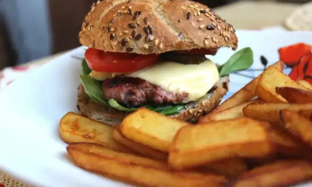 Pyszne, prawdziwe burgery przepis na domowy obiad. Soczysty kotlet, ser, warzywa i chrupiące frytki na talerzu.