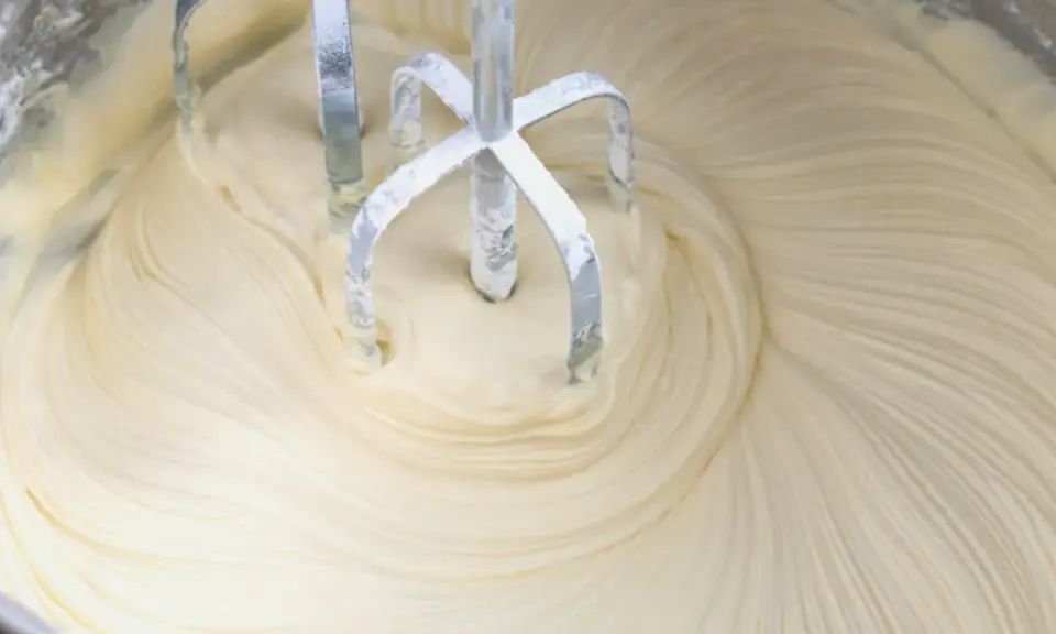 Mieszadła miksera zagłębiają się w puszysty krem z mascarpone i białej czekolady, tworząc faliste wzory.