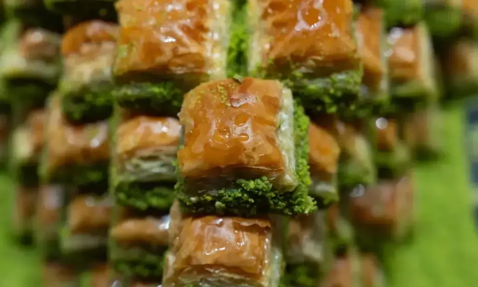 Słodka, złocista baklava, co to za przysmak! Warstwy ciasta filo, orzechów i syropu, posypane zielonymi pistacjami.