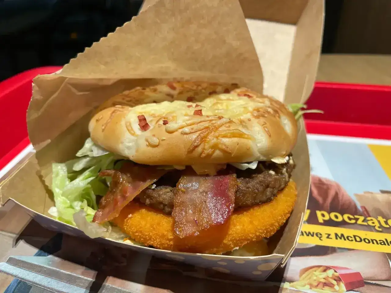 Burger drwala w papierowym opakowaniu, z chrupiącym bekonem i serem na bułce. Pyszny posiłek gotowy do zjedzenia.