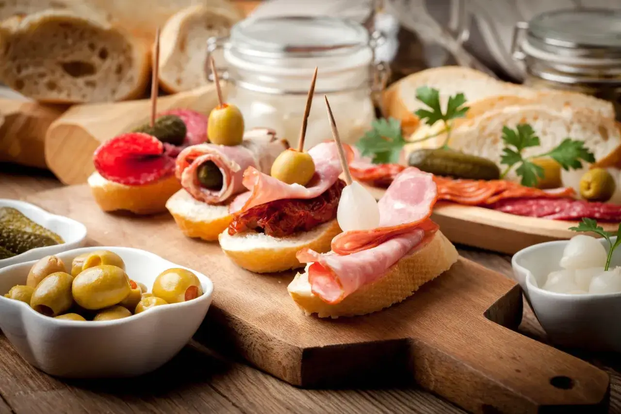 Pyszne pinchos z wędliną, oliwkami i suszonymi pomidorami na chrupiącym pieczywie. Idealne na przekąskę!