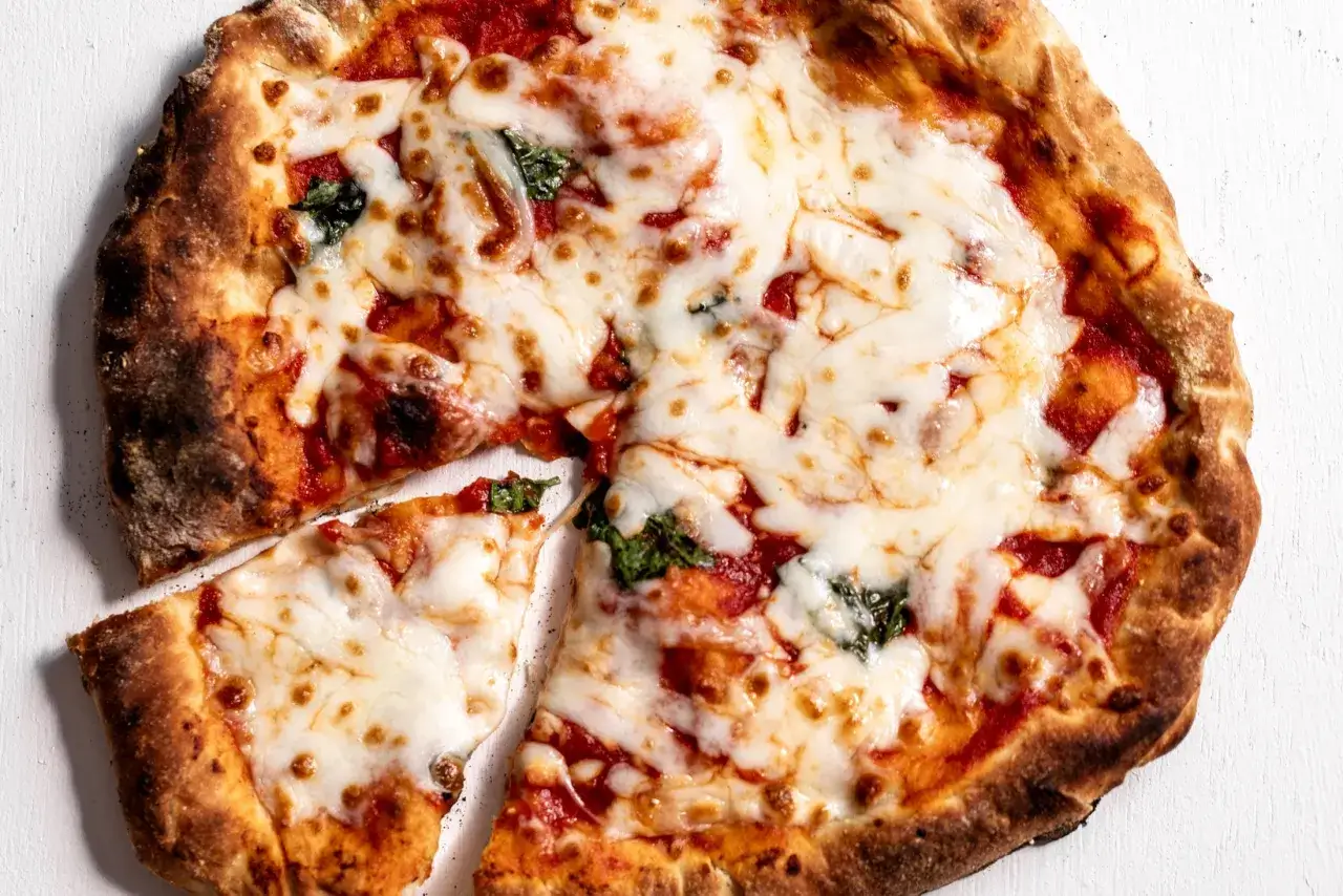 Apetyczna pizza z ciągnącym serem i bazylią. Zastanawiasz się, ile kalorii ma średnia pizza?