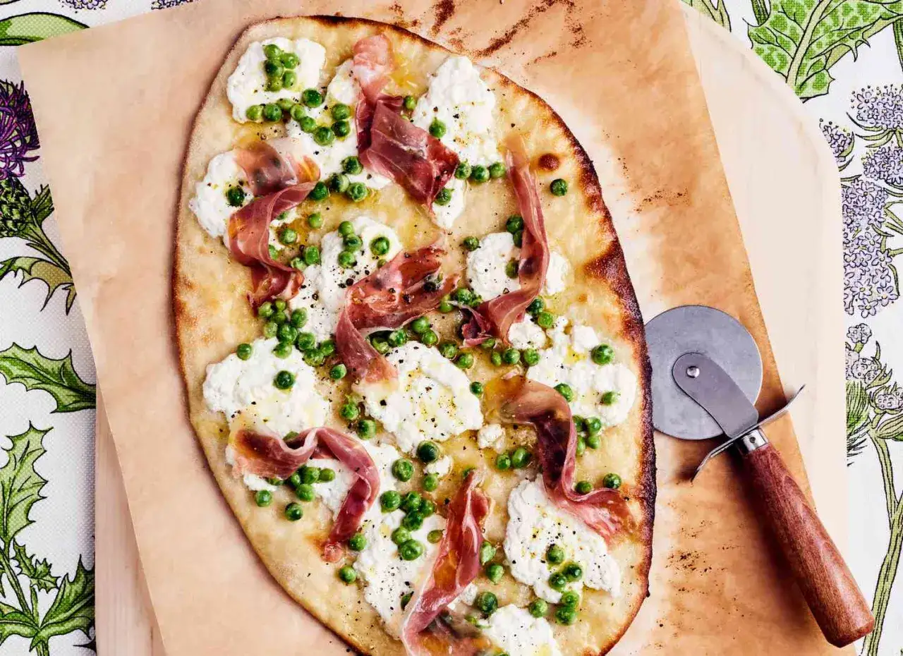 Pyszna pizza rzymska z ricottą, groszkiem i szynką parmeńską, posypana świeżo mielonym pieprzem.
