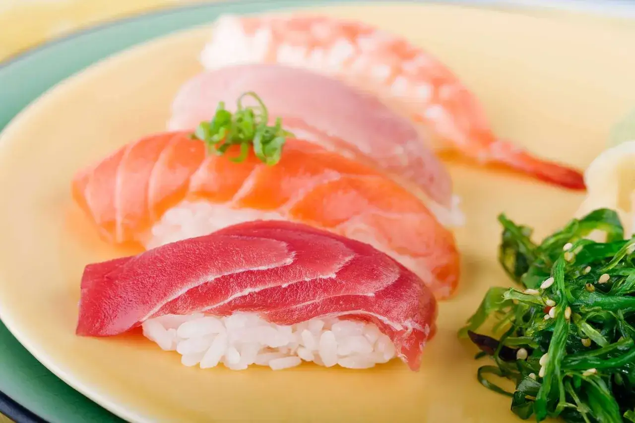 Piękne składniki do sushi: nigiri z tuńczyka, łososia, krewetki i sałatka wakame.