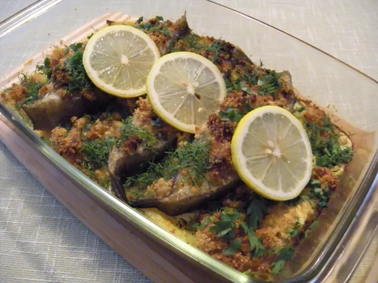 Pyszny halibut smażony w panierce, udekorowany plasterkami cytryny i świeżym koperkiem.
