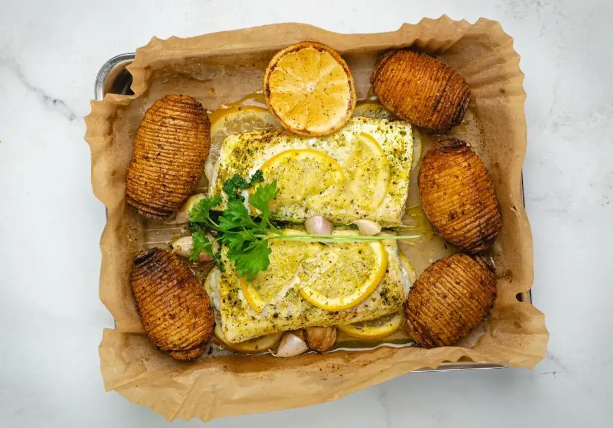 Pyszna ryba z airfryer, podana z pieczonymi ziemniakami hasselback, cytryną i czosnkiem.
