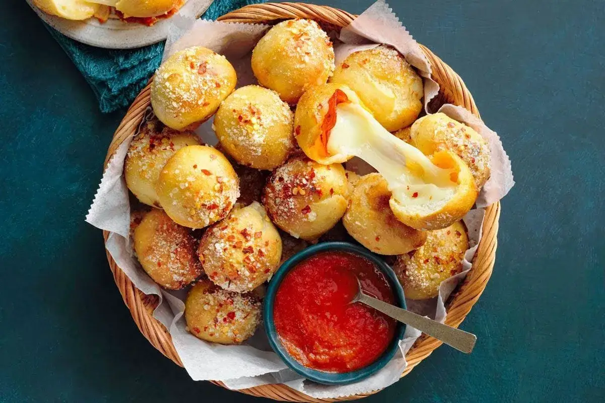 Pyszne kulki z ciasta na pizzę, nadziewane serem i papryką, posypane parmezanem i płatkami chili. Idealne do sosu pomidorowego.