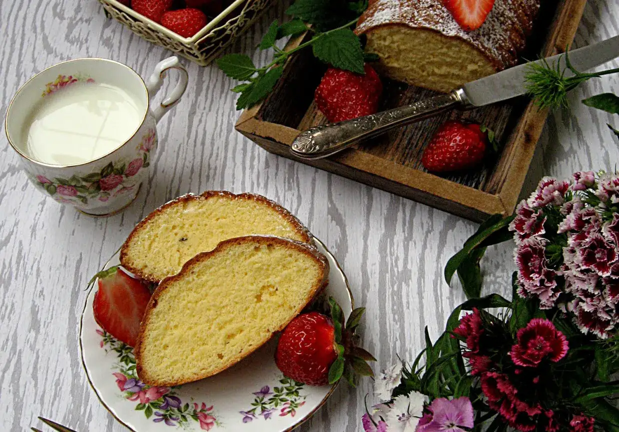 Puszyste ciasto z żółtek, pokrojone na plastry, podane z mlekiem i świeżymi truskawkami.