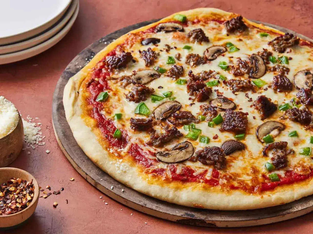 Pyszna pizza capriciosa z kawałkami mięsa, pieczarkami i zieloną papryką, posypana płatkami chili.