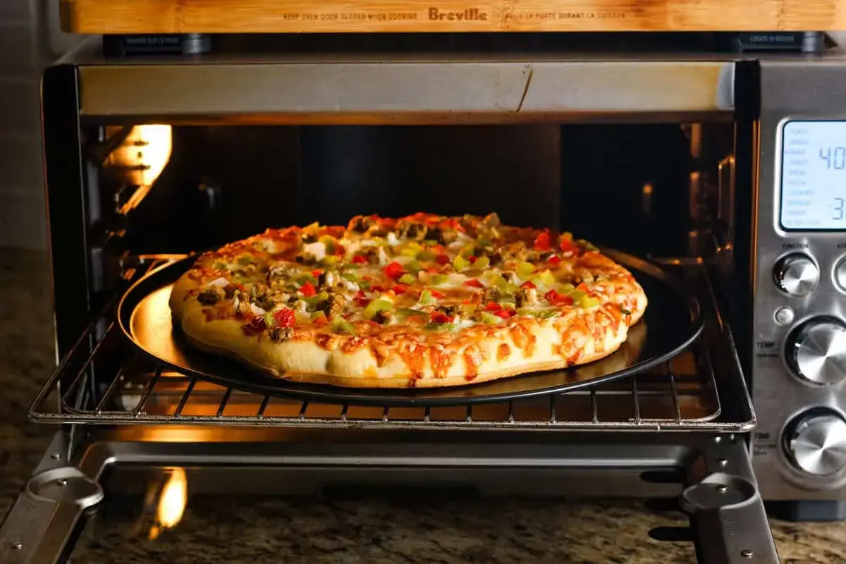 Pyszna pizza Guiseppe z kolorowymi paprykami i serem piecze się w piekarniku.