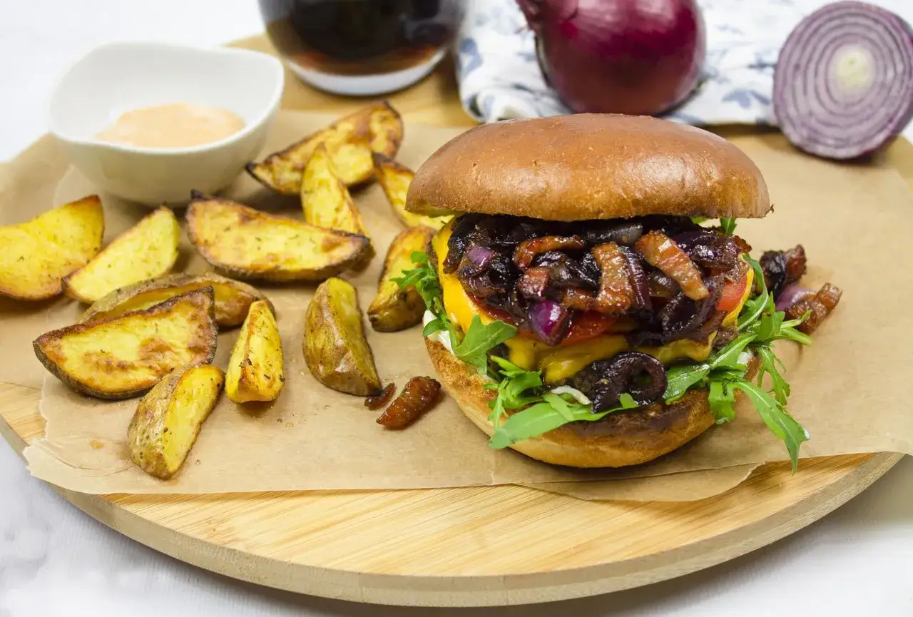 Gotowe hamburgery z Biedronki jak przyrządzić: soczysty burger z karmelizowaną cebulką i frytkami.