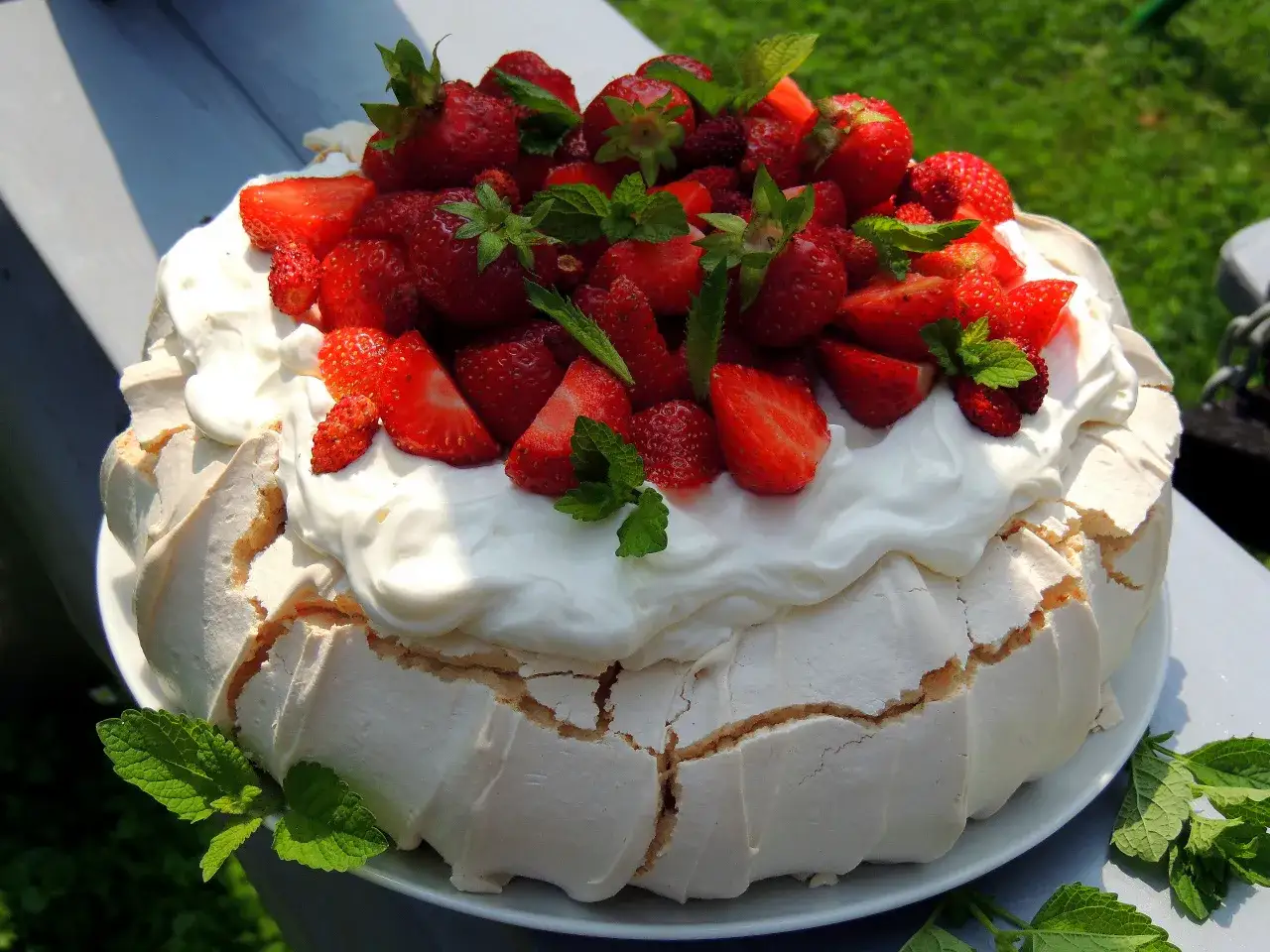 Beza Pavlova, która zawsze wychodzi, z bitą śmietaną i świeżymi truskawkami, ozdobiona miętą. Idealna na letnie popołudnie.