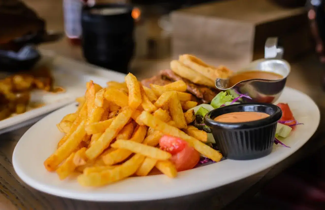 Porcja frytek z sosem i sałatką. Zastanawiasz się, ile kalorii ma porcja frytek?