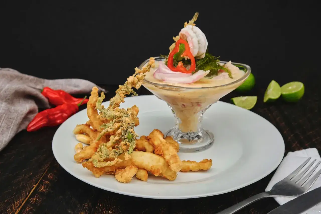 Pyszne ceviche z krewetkami i chrupiącymi kalmarami, podane z limonką i papryczkami chili.