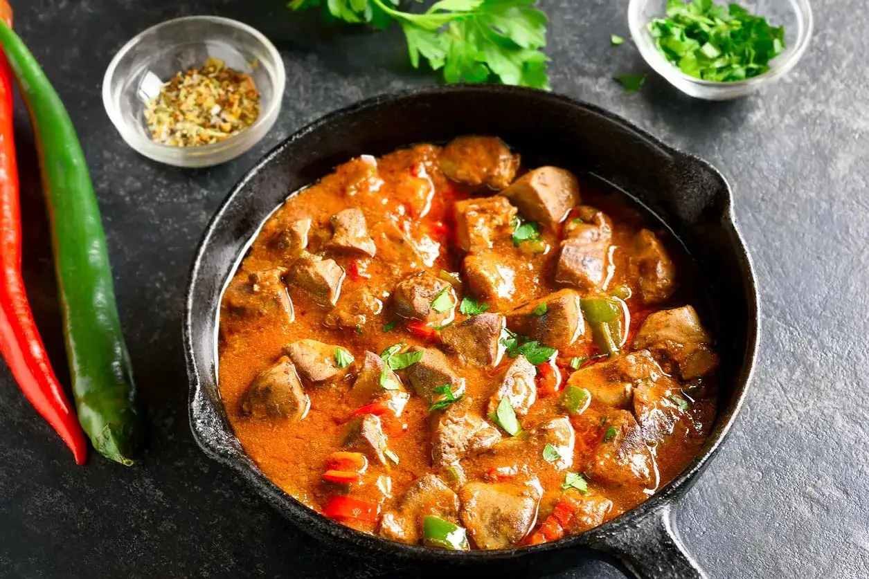 Gulasz z wątróbki w sosie pomidorowym, idealny na sobotni obiad. Podany w żeliwnej patelni z papryczkami chili i natką pietruszki.