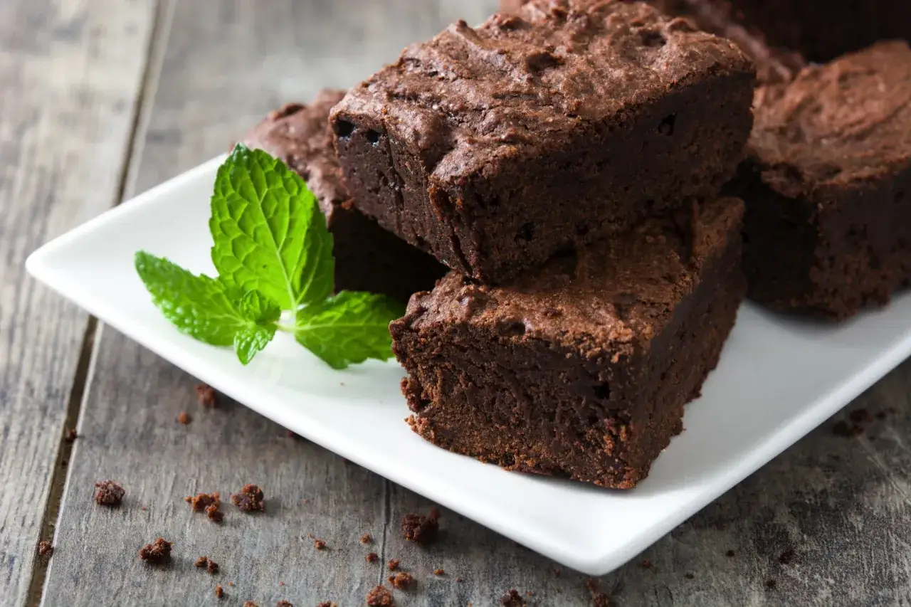 Pyszne brownie z airfryera na białym talerzyku, ozdobione listkami mięty. Idealne na deser!