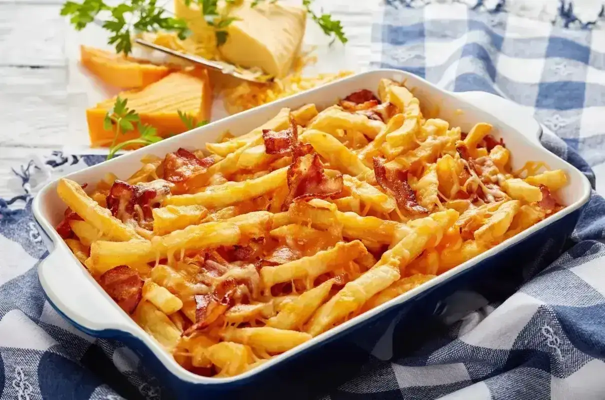 Pyszne frytki z serem i chrupiącym boczkiem, zapieczone w naczyniu. Idealna przekąska dla każdego miłośnika serowych smaków.