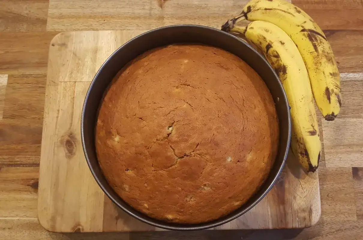 Puszyste ciasto bananowe na oleju, świeżo upieczone, z dojrzałymi bananami obok. Idealne na podwieczorek.