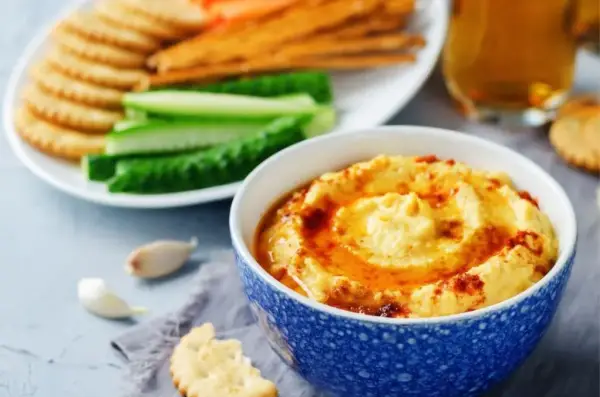 Pyszny, kremowy hummus, idealny jako sos do frytek, podany z chrupiącymi krakersami i świeżymi warzywami.